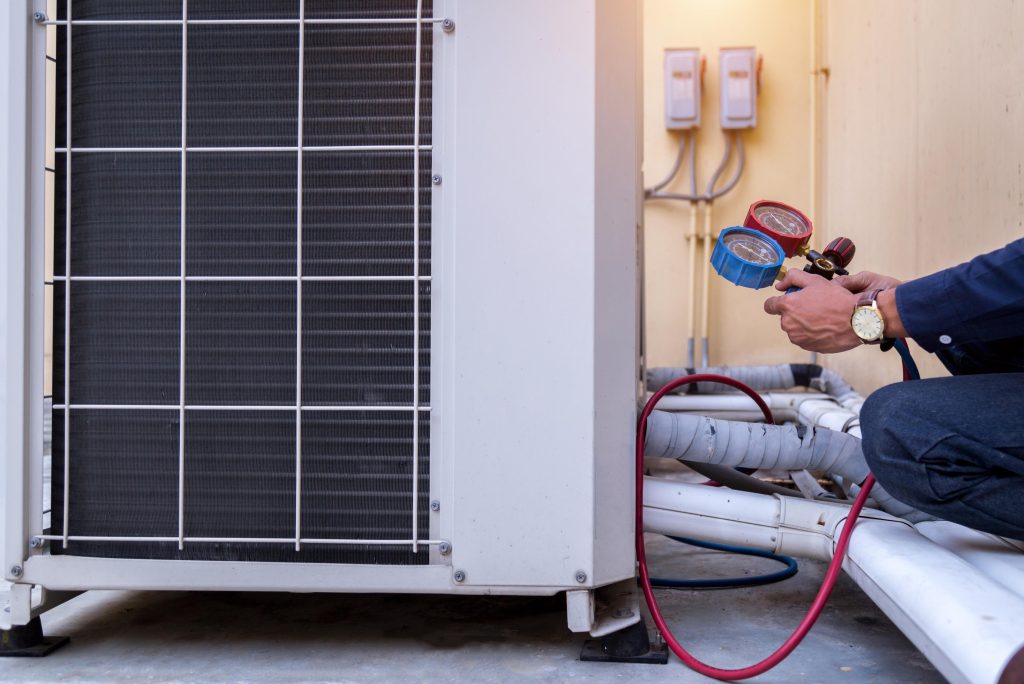 Technician using pressure gauges on a heat pump during repair, highlighting professional HVAC services for efficient heating and cooling in Riverside, CA.