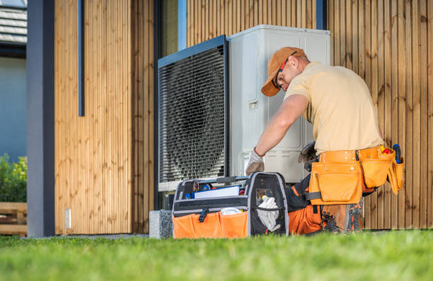 Technician servicing a heat pump unit outside a home, emphasizing professional HVAC installation and maintenance services for efficient heating and cooling.