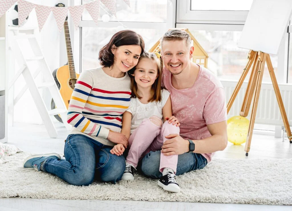 Smiling family sitting on living room floor