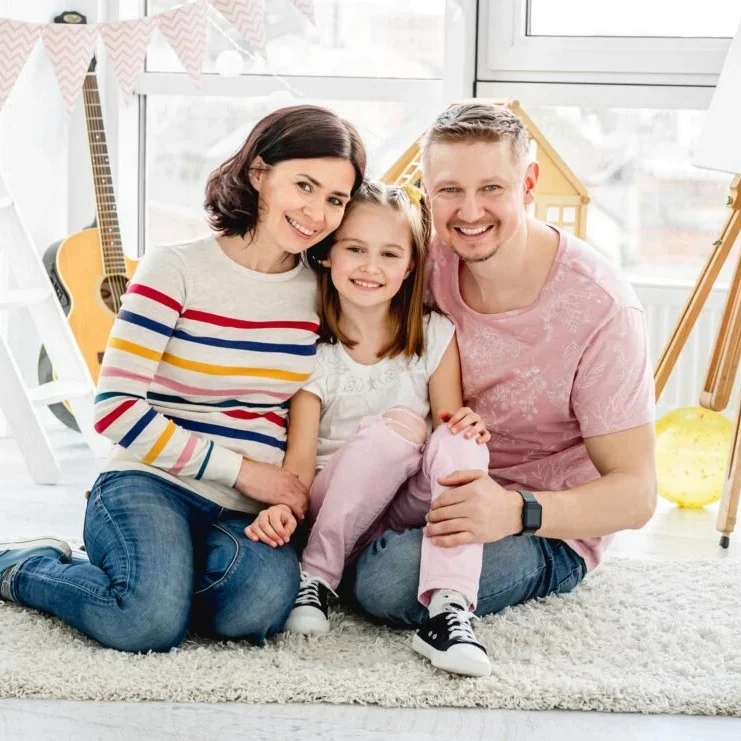 Smiling family sitting on living room floor
